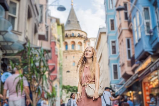 Portrait of beautiful woman tourist with view of Galata tower in Beyoglu, Istanbul, Turkey. Turkiye.