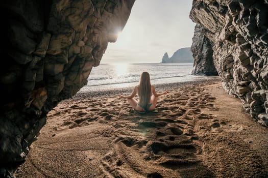 Middle aged well looking woman with black hair doing Pilates with the ring on the yoga mat near the sea on the pebble beach. Female fitness yoga concept. Healthy lifestyle, harmony and meditation.