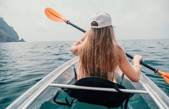 Woman in kayak back view. Happy young woman with long hair floating in transparent kayak on the crystal clear sea. Summer holiday vacation and cheerful female people having fun on the boat.