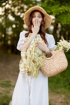 portrait of a surprised woman in a wicker hat and with a plaid in her hands in nature. High quality photo