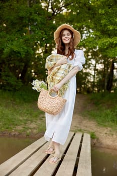 a woman in a light dress, with a plaid and a wicker basket in her hands, is spinning on the pier. High quality photo