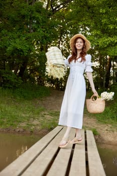 a woman in a light dress, with a plaid and a wicker basket in her hands, is spinning on the pier. High quality photo