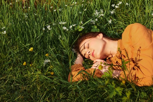 a close horizontal photo of a happy woman lying in the grass with her eyes closed and a pleasant smile on her face. High quality photo