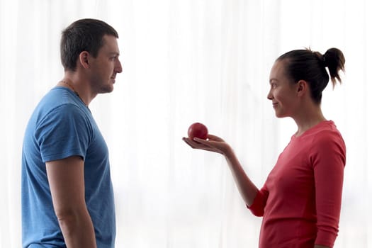 Woman gives apple to man. Man eats an Apple