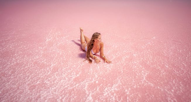 Woman in a pink salt lake. She lies in a white bathing suit. Wanderlust photo for memory.