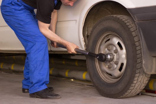 Mechanic changes the wheel of the car in the auto service