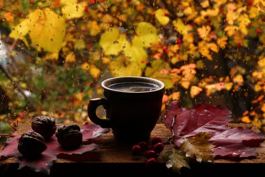 Cup of hot coffee and drops on the autumn window