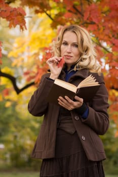 Romantic young woman dreams under an autumn tree