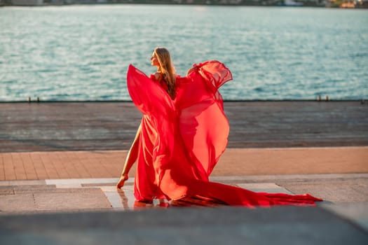 Sunrise red dress. A woman in a long red dress against the backdrop of sunrise, bright golden light of the sun's rays. The concept of femininity, harmony