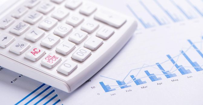 White calculator and report with chart and graph, concept of annual financial profit overview, banking and investment, close up, copy space, macro