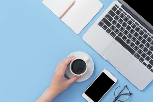 Business concept. Clean bright light blue office table desk, minimal style with laptop coffee and smart phone, copy space, top view, flat lay, mockup