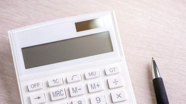 White calculator and pen on bright wooden table, analytics and statistics of financial profit, investment risk concept, copy space, top view flat lay