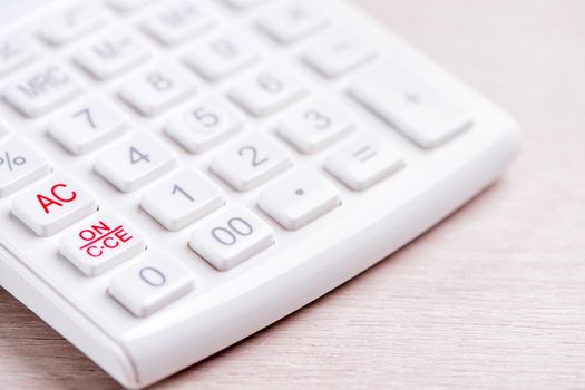 White calculator and pen on bright wooden table, analytics and statistics of financial profit, investment risk concept, copy space, macro, close up