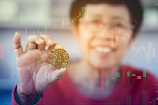 Senior woman smiling holding bitcoin cryptocurrency as electronic payment,   technology money market concept
