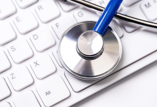 Stethoscope on computer keyboard on white background. Physician write medical case long term care treatment concept, close up, macro, copy space