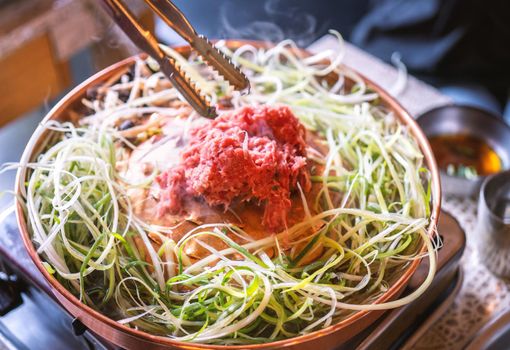 Beef barbecue bulgogi in South Korea restaurant in Seoul, lifestyle fresh korean food cuisine on copper pan with sliced grill, close up, copy space
