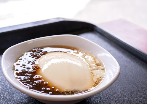 Popular Taiwan gourmet - Dessert of tapioca pearl ball (bubble) mixed bean curd tofu pudding (douhua, dou hua) in white bowl, close up, lifestyle