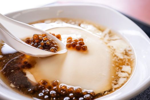 Popular Taiwan gourmet - Dessert of tapioca pearl ball (bubble) mixed bean curd tofu pudding (douhua, dou hua) in white bowl, close up, lifestyle
