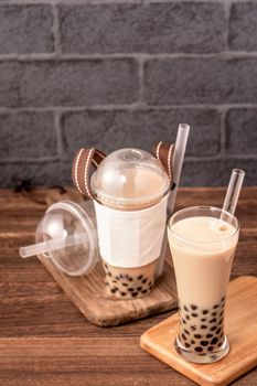 Takeout with disposable item concept popular Taiwan drink bubble milk tea with plastic cup and straw on wooden table background, close up, copy space