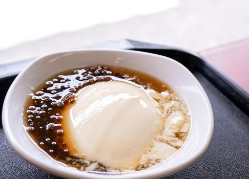 Popular Taiwan gourmet - Dessert of tapioca pearl ball (bubble) mixed bean curd tofu pudding (douhua, dou hua) in white bowl, close up, lifestyle