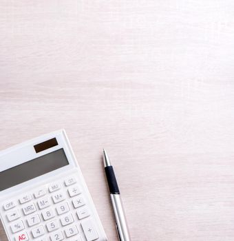 White calculator and pen on bright wooden table, analytics and statistics of financial profit, investment risk concept, copy space, top view flat lay