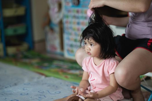 Mother and little girl drying hair with hairdryer after having bath