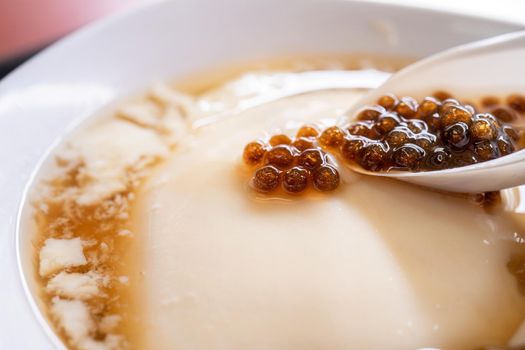 Popular Taiwan gourmet - Dessert of tapioca pearl ball (bubble) mixed bean curd tofu pudding (douhua, dou hua) in white bowl, close up, lifestyle