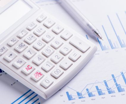 White calculator and report with chart and graph, concept of annual financial profit overview, banking and investment, close up, copy space, macro