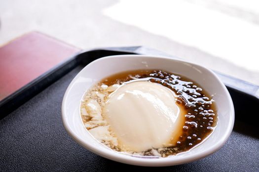 Popular Taiwan gourmet - Dessert of tapioca pearl ball (bubble) mixed bean curd tofu pudding (douhua, dou hua) in white bowl, close up, lifestyle