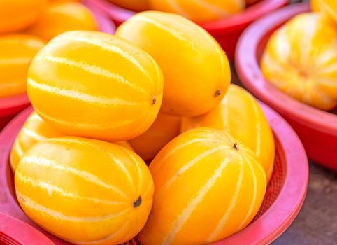 Delicious korean stripe yellow melon fruit food in red plastic basket at tradition market afternoon, Seoul, South Korea, harvest concept, close up.
