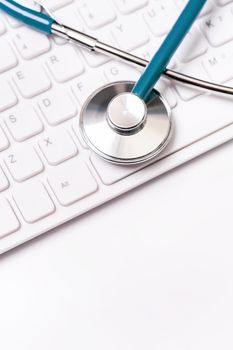 Stethoscope on computer keyboard on white background. Physician write medical case long term care treatment concept, close up, macro, copy space
