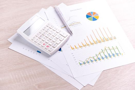 White calculator and report with chart and graph, concept of annual financial profit overview, banking and investment, close up, copy space, macro