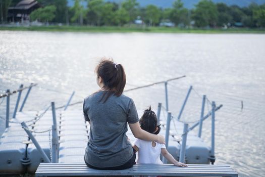 mother and her daughter sitting and looking to the river
