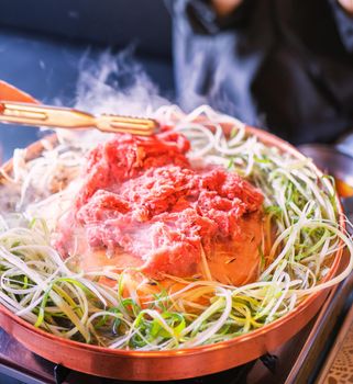 Beef barbecue bulgogi in South Korea restaurant in Seoul, lifestyle fresh korean food cuisine on copper pan with sliced grill, close up, copy space