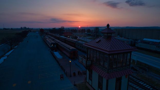 Sunrise With Blue, Red Sky and Clouds Looking Over a Train Station and Yard