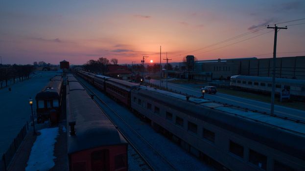 Sunrise With Blue, Red Sky and Clouds Looking Over a Train Station and Yard