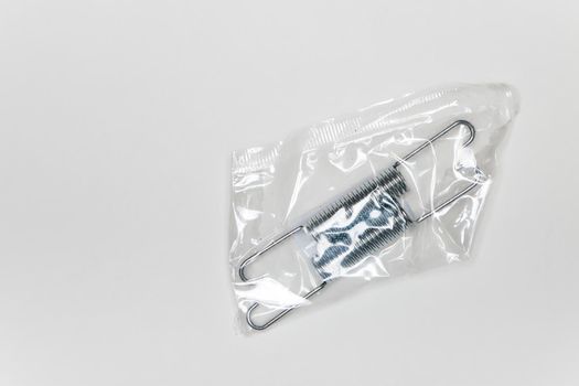 Two metal springs in a package, parts for car repair. A set of spare parts for servicing vehicle calipers. Details on white background, copy space available.