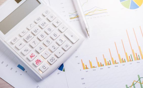 White calculator and report with chart and graph, concept of annual financial profit overview, banking and investment, close up, copy space, macro