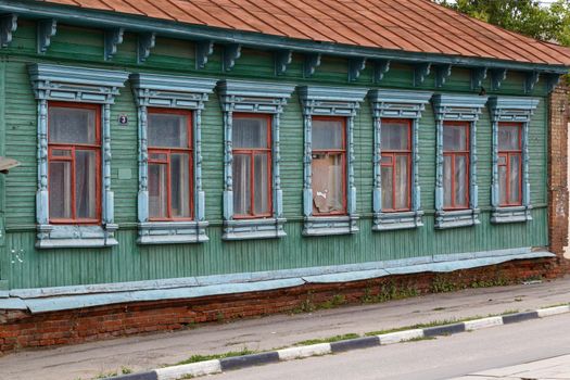 classic russian wooden house with 6 windows on it, front view poor condition on city street