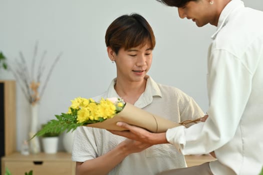 Loving young asian man giving a bunch of flowers to his boyfriend. LGBTQ people lifestyle and love emotion.