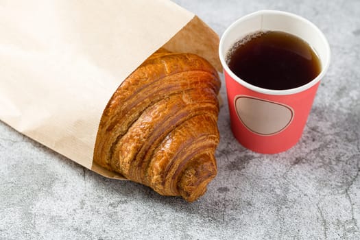 Croissant on a white porcelain plate with tea on the side