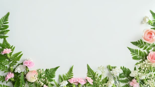 Pink roses, carnation and fern leaves on white background. Spring floral background, frame, copy space for text.