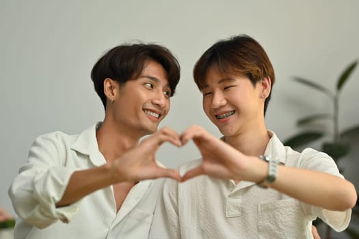 Cheerful young gay couple making heart with their hands. LGBT, love and lifestyle relationship concept.