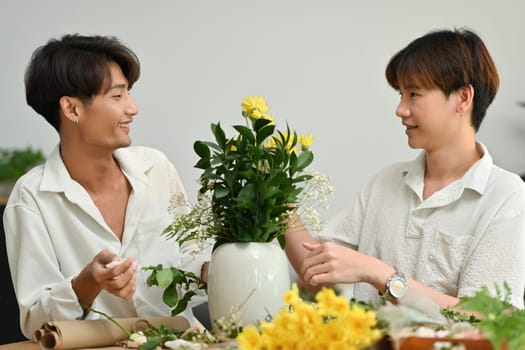 Affectionate romantic male gay couple spending time together, enjoying arranging flowers in cozy home. LGBT, homosexual and love.