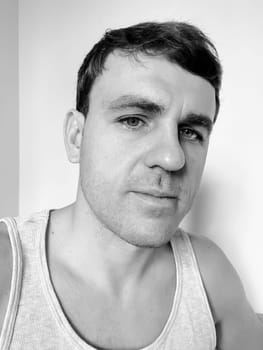 Portrait of a tired young man in a tank top. Black and white photo. High quality photo