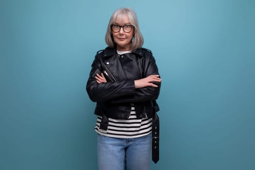 middle age business. 60s mature woman in gray hair in a stylish youth look looks cool on a blue background.