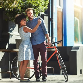 Happiness, selfie and diversity couple of city friends with outdoor picture memory of date, romance or morning bike commute. Bicycle, urban bonding and marriage people post photo to social media app.