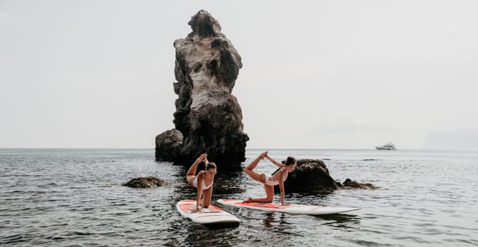 Woman sup yoga. Middle age sporty woman practising yoga pilates on paddle sup surfboard. Female stretching doing workout on sea water. Modern individual hipster outdoor summer sport activity