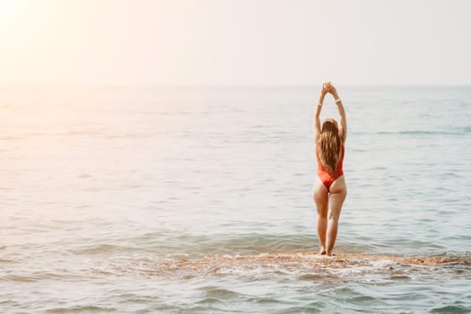 Woman sea yoga. Back view of free calm happy satisfied woman with long hair standing on top rock with yoga position against of sky by the sea. Healthy lifestyle outdoors in nature, fitness concept.