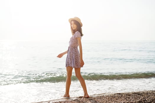 Lonely romantic young woman walks on the seashore at sunset